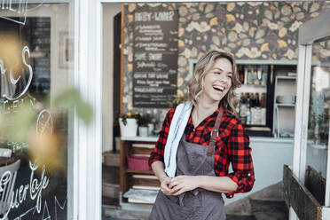 Cheerful businesswoman standing at cafe entrance - JOSEF04498