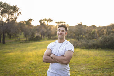 Handsome sports person standing with arms crossed during sunset - RSGF00690