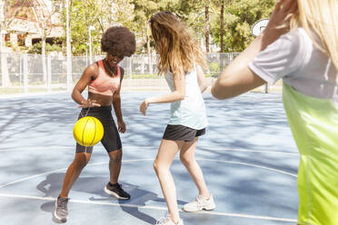 Freundinnen spielen Basketball auf einem Sportplatz im Park - IFRF00579