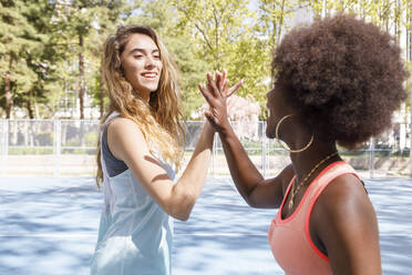 Junge Frauen geben sich auf dem Sportplatz die Hand - IFRF00583