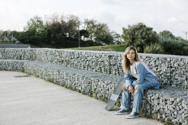 Woman sitting on stone bench in skateboard park - XLGF01792