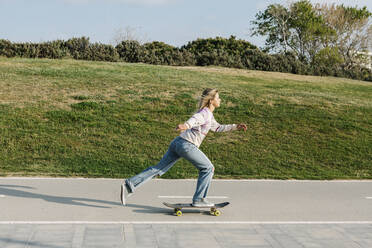 Mittlere erwachsene Frau, die auf der Straße Skateboard fährt - XLGF01799