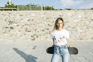 Blonde Frau mit Skateboard an einem sonnigen Tag im Park - XLGF01806