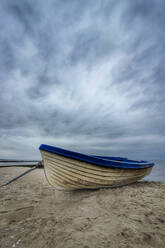 Bewölkter Himmel über einem Ruderboot am Sandstrand - NGF00747