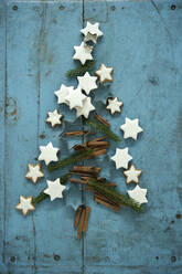 Weihnachten Zimt Stern geformte Kekse zusammen mit Zimt und Nadel Zweige in Weihnachtsbaum auf blauen rustikalen hölzernen Hintergrund angeordnet - ASF06755