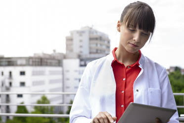 Medizinische Fachkraft mit digitalem Tablet auf dem Krankenhausbalkon - BMOF00638