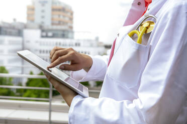 Medizinische Fachkraft mit digitalem Tablet auf dem Balkon - BMOF00640