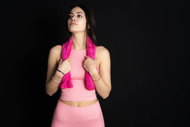Thoughtful female athlete holding napkin in front of black background - GIOF12631