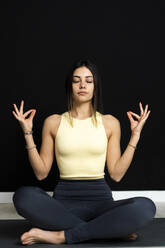Sportlerin meditiert im Yogastudio sitzend - GIOF12649