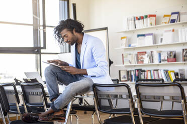 Man using digital tablet while sitting on table in library - BMOF00651