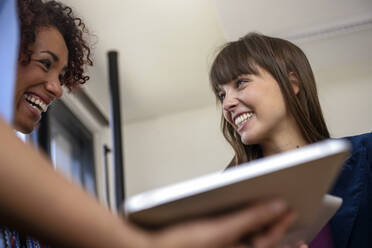 Smiling female entrepreneurs looking at each other at office - BMOF00686