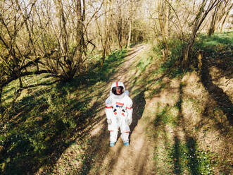 Astronautin im Raumanzug auf einem Waldweg - MEUF02774