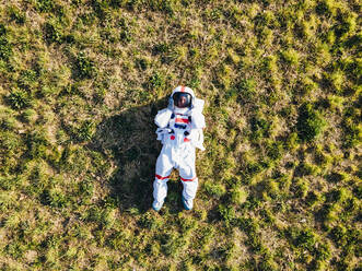 Junge Astronautin auf einer Wiese liegend - MEUF02776