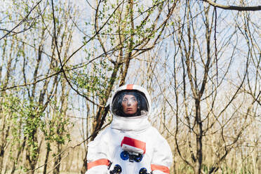 Weibliche Astronautin mit Raumanzug und Helm steht im Wald - MEUF02795