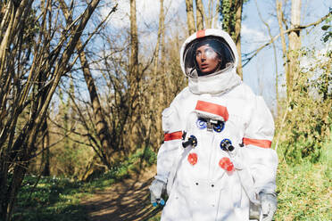 Young female astronaut exploring forest during sunny day - MEUF02801