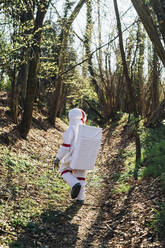 Junger Astronaut auf einem Waldweg an einem sonnigen Tag - MEUF02804