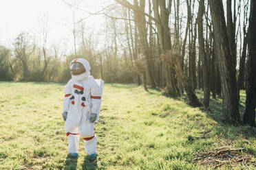 Female explorer wearing space suit standing in forest on sunny day - MEUF02812