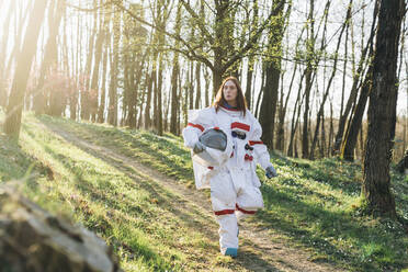 Junge Astronautin mit Weltraumhelm beim Gehen auf einem Feldweg - MEUF02817