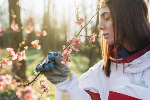 Young female explorer with freckles smelling flower in forest - MEUF02819