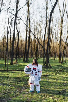 Astronautin mit Weltraumhelm im Wald stehend - MEUF02821