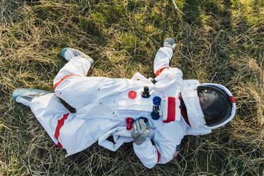 Weibliche Astronautin auf dem Boden liegend im Wald - MEUF02824