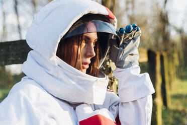 Weibliche Astronautin mit Weltraumhelm schaut im Wald weg - MEUF02835