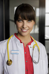 Lächelnde Ärztin mit Stethoskop in einem medizinischen Gebäude - BMOF00706