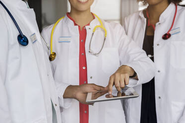 Male and female doctors discussing over digital tablet in hospital - BMOF00707