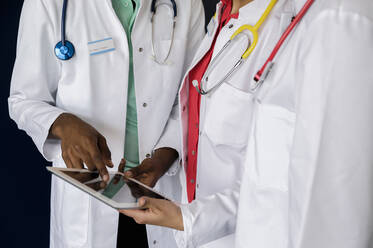 Männlicher Arzt diskutiert mit weiblichen Kollegen im Krankenhaus über ein digitales Tablet - BMOF00709