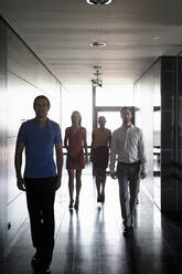 Male and female entrepreneurs walking in corridor at office - BMOF00715