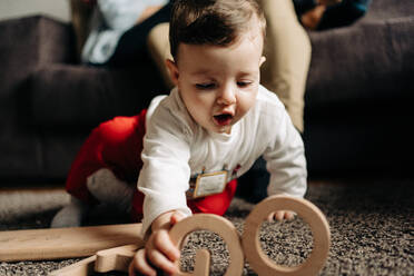 Adorable kleines Baby spielt auf dem Boden mit Holzspielzeug mit Tiago Namen Buchstaben - ADSF24197