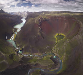 Amazing view of curvy blue river loop streaming on rough hilly terrain covered with lush abundant vegetation in Iceland - ADSF24224
