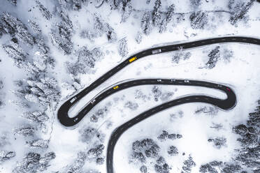 Luftaufnahme von Autos, die auf engen Kurven einer Bergstraße im Schnee fahren, Schweiz, Europa - RHPLF19718