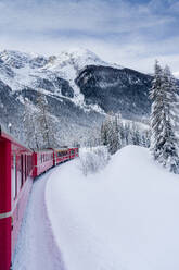 Red Bernina Express train crossing the snowy landscape in winter, Preda Bergun, Albula Valley, Graubunden Canton, Switzerland, Europe - RHPLF19765