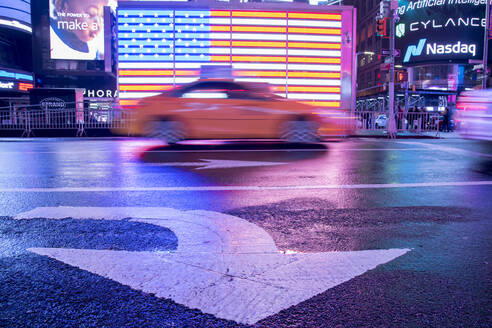 Unscharfes Taxi vor einer beleuchteten Flagge der Vereinigten Staaten von Amerika am Times Square, New York City, Vereinigte Staaten von Amerika, Nordamerika - RHPLF19779