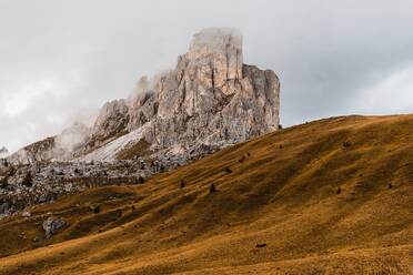 Malerische Landschaft mit rauen steilen Felsgipfeln und mit gelbem Gras bedeckten Hügeln unter Wolken in den Dolomiten in Italien - ADSF24236