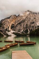 Erstaunlicher Blick auf die Bergkette der Dolomiten mit grünem Seewasser, in dem sich raue, mit Nebel und Wolken bedeckte Felshänge spiegeln, in Italien - ADSF24237