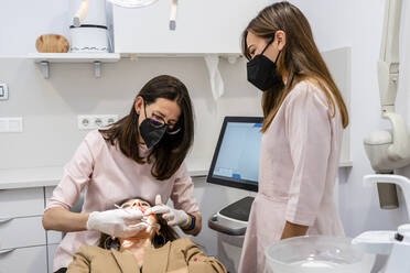 Female dentists examining patient's teeth in clinic - DLTSF01889