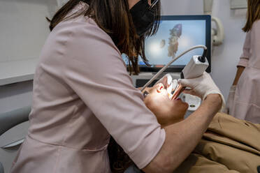 Female dentist checking patient in clinic - DLTSF01891