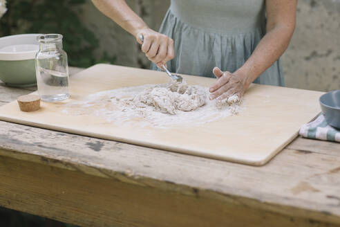 Reife Frau macht Teig auf Holztisch - ALBF01598