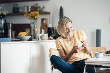 Lächelnde Frau, die zu Hause ein Mobiltelefon benutzt - JOSEF04524