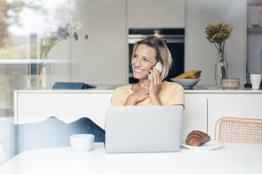 Smiling female entrepreneur talking on mobile phone - JOSEF04535