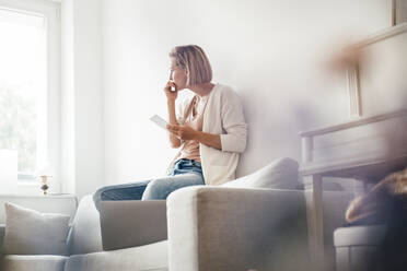 Thoughtful woman day dreaming while sitting on sofa at home - JOSEF04547