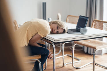 Müde weibliche Berufstätige schlafen auf dem Tisch zu Hause - JOSEF04559