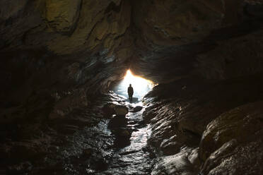 New Zealand, South Island, Fiordland National Park, Man at entrance of cave - WVF01865