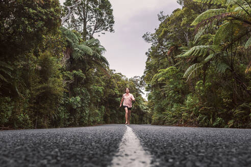 Neuseeland, Nordinsel, Northland, Junger Mann läuft auf Straße durch Waipoua Forest - WVF01872