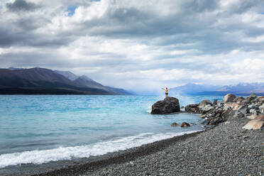 Neuseeland, Canterbury, Junger Mann genießt den steinigen Strand am Lake Tekapo - WVF01899