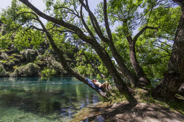 Young man relaxing on bank of Waikato River in summer - WVF01919