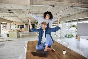 Couple with arms outstretched enjoying on table at loft - FMKF07151