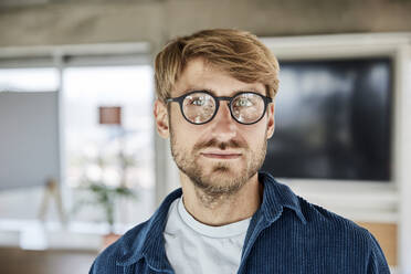 Blonder Mann mit Brille, der in einem Loft nachdenkt - FMKF07159